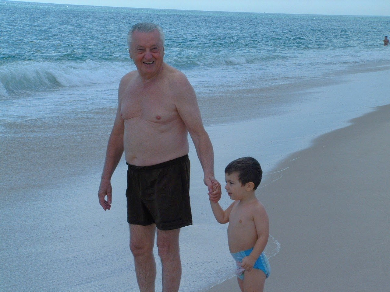 Papa walking on the beach with a young Eitan